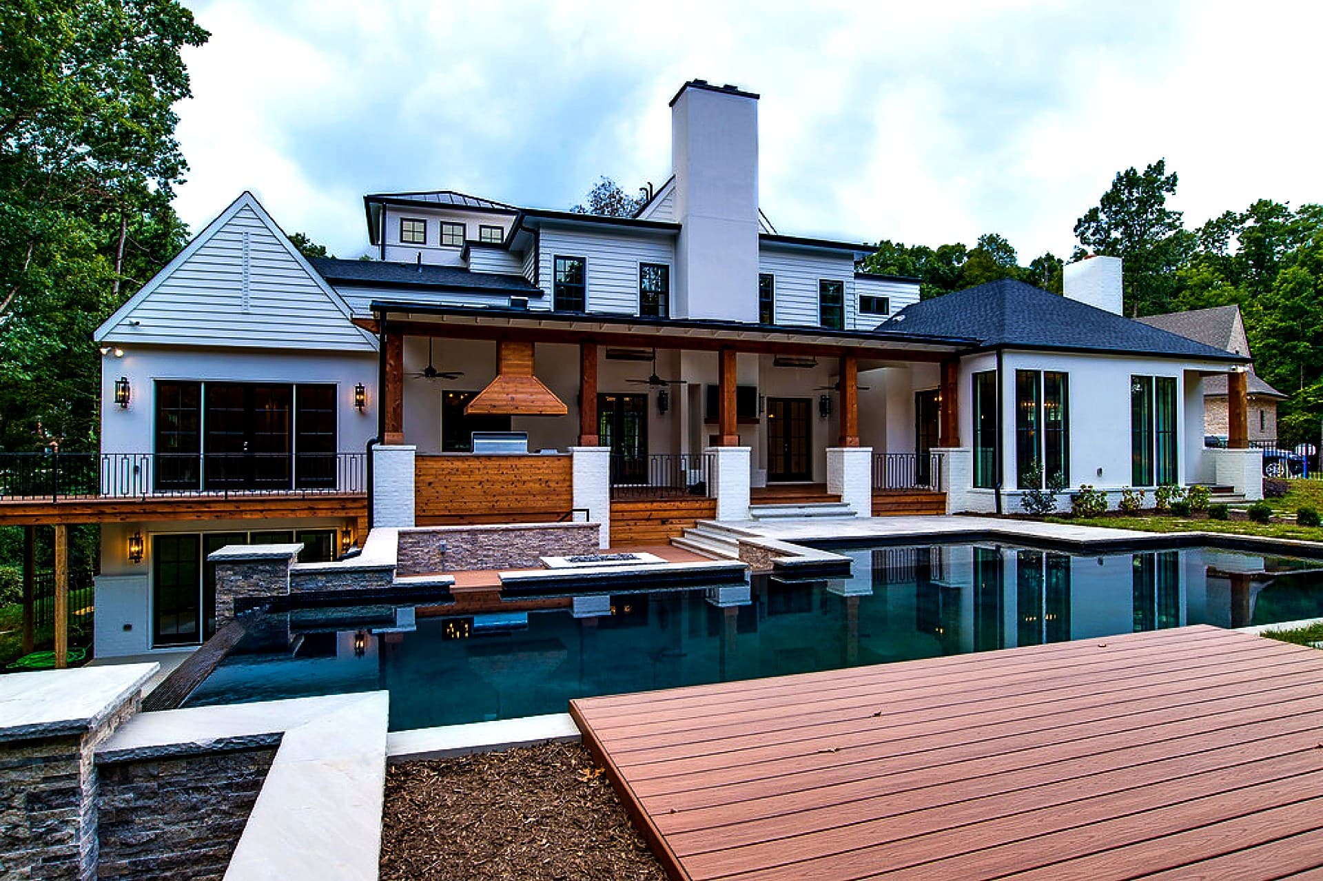 Contemporary geometric pool with dark finish, raised spa, and covered outdoor kitchen